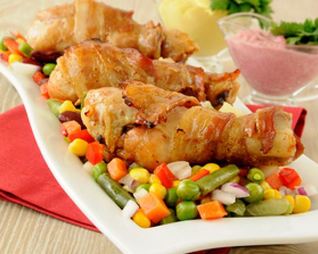 Жареные куриные ножки, обернутые в бекон с овощами